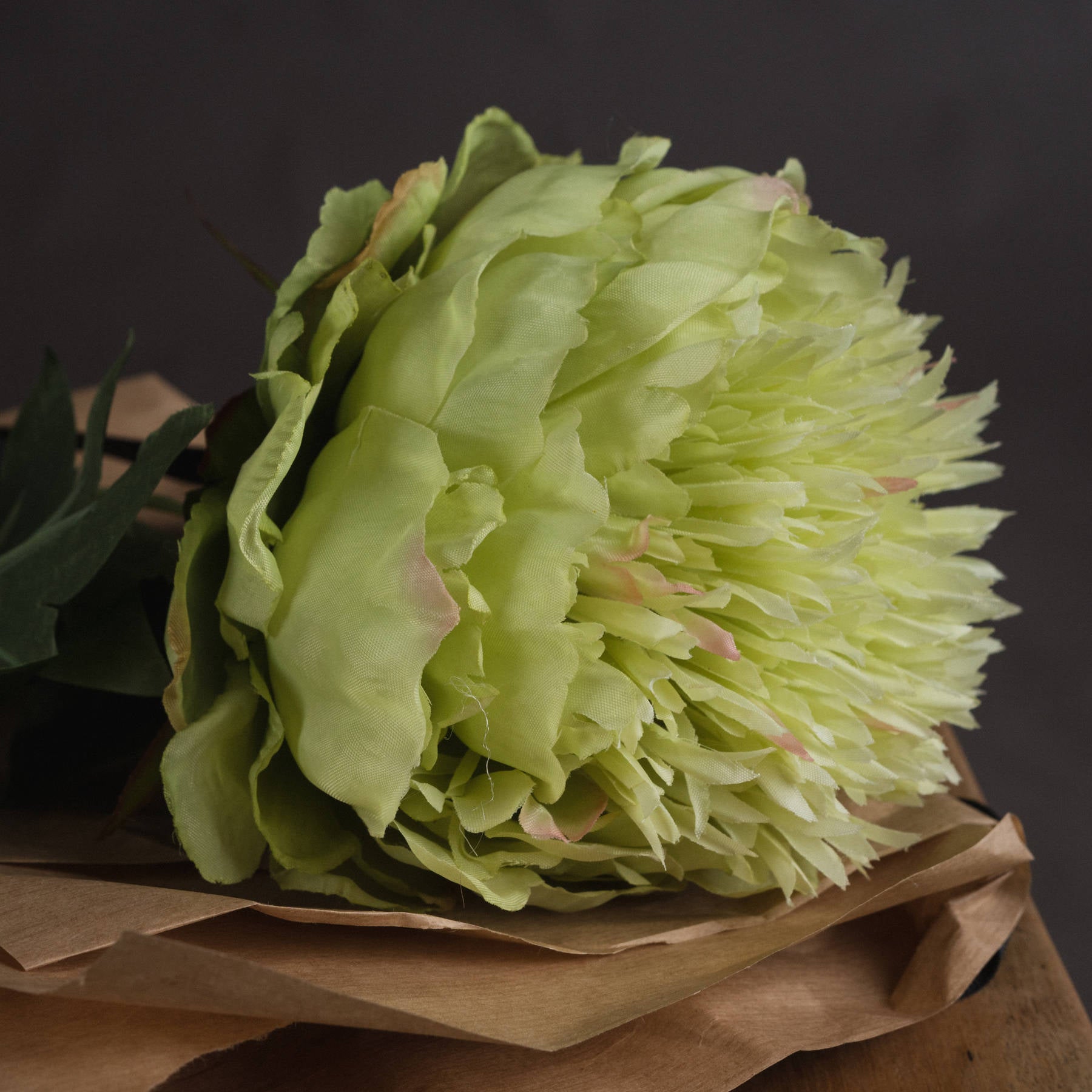 Light green flower bouquet on brown paper against a dark background