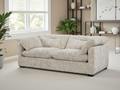 Beige sofa in a living room with a window, plants, and shelves in the background.