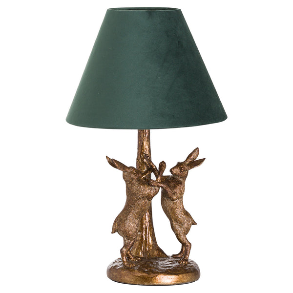 Decorative table lamp with bronze rabbit figures and a green lampshade on a white background