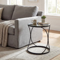 Round black metal side table with a mug, books, and plant in a living room setting.