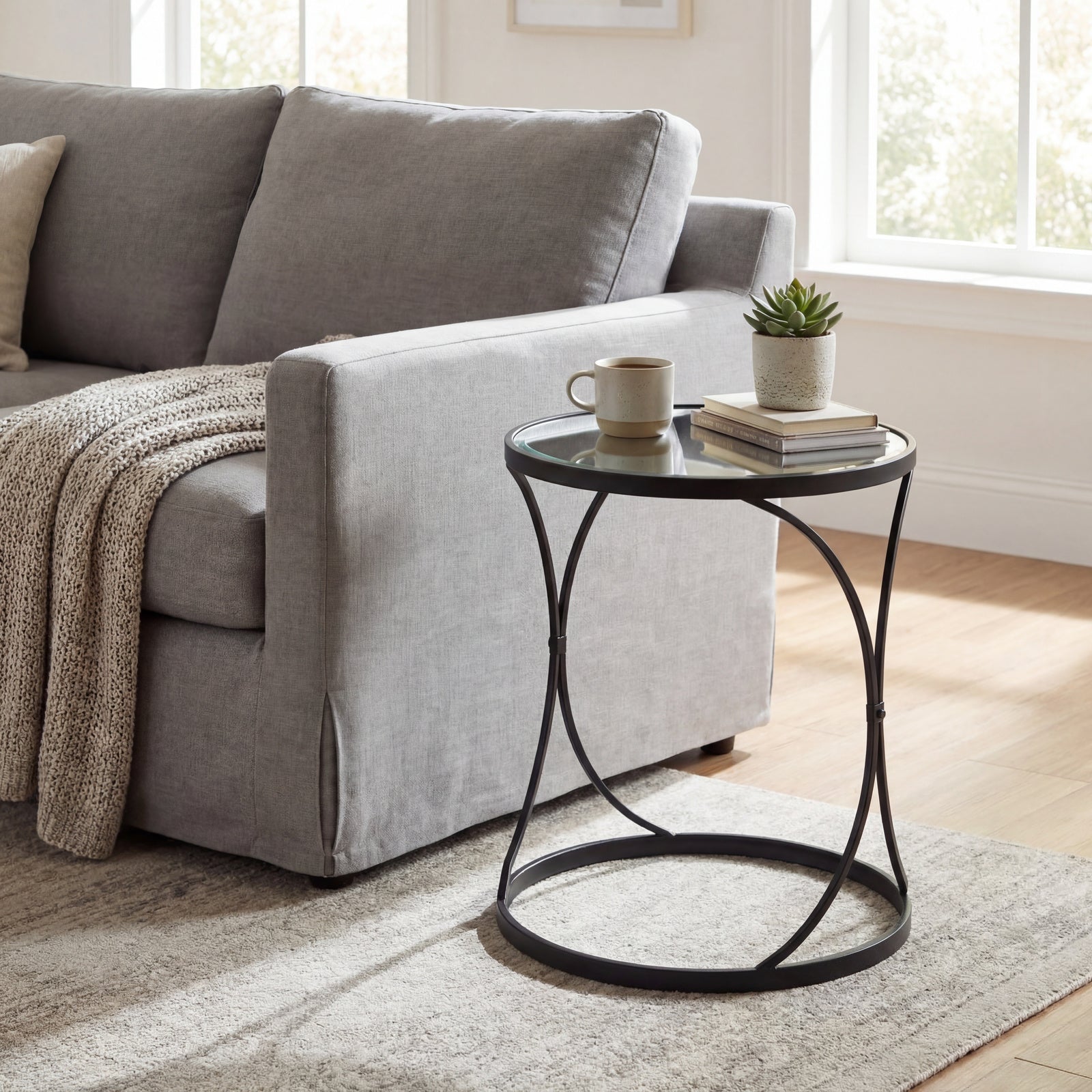 Round black metal side table with a mug, books, and plant in a living room setting.