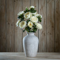 White vase with artificial flowers against a wooden panel background