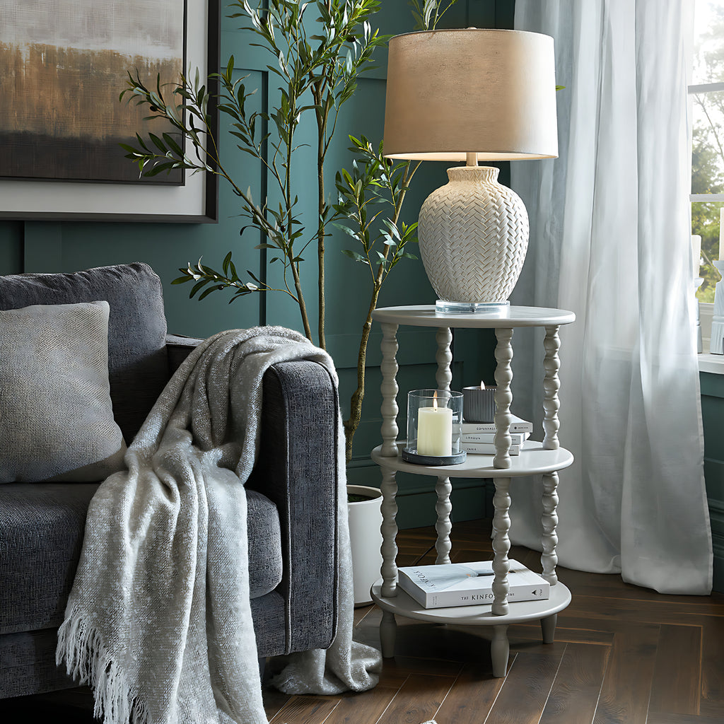 Living room with gray sofa, white lamp, and decorative items on a wooden floor.