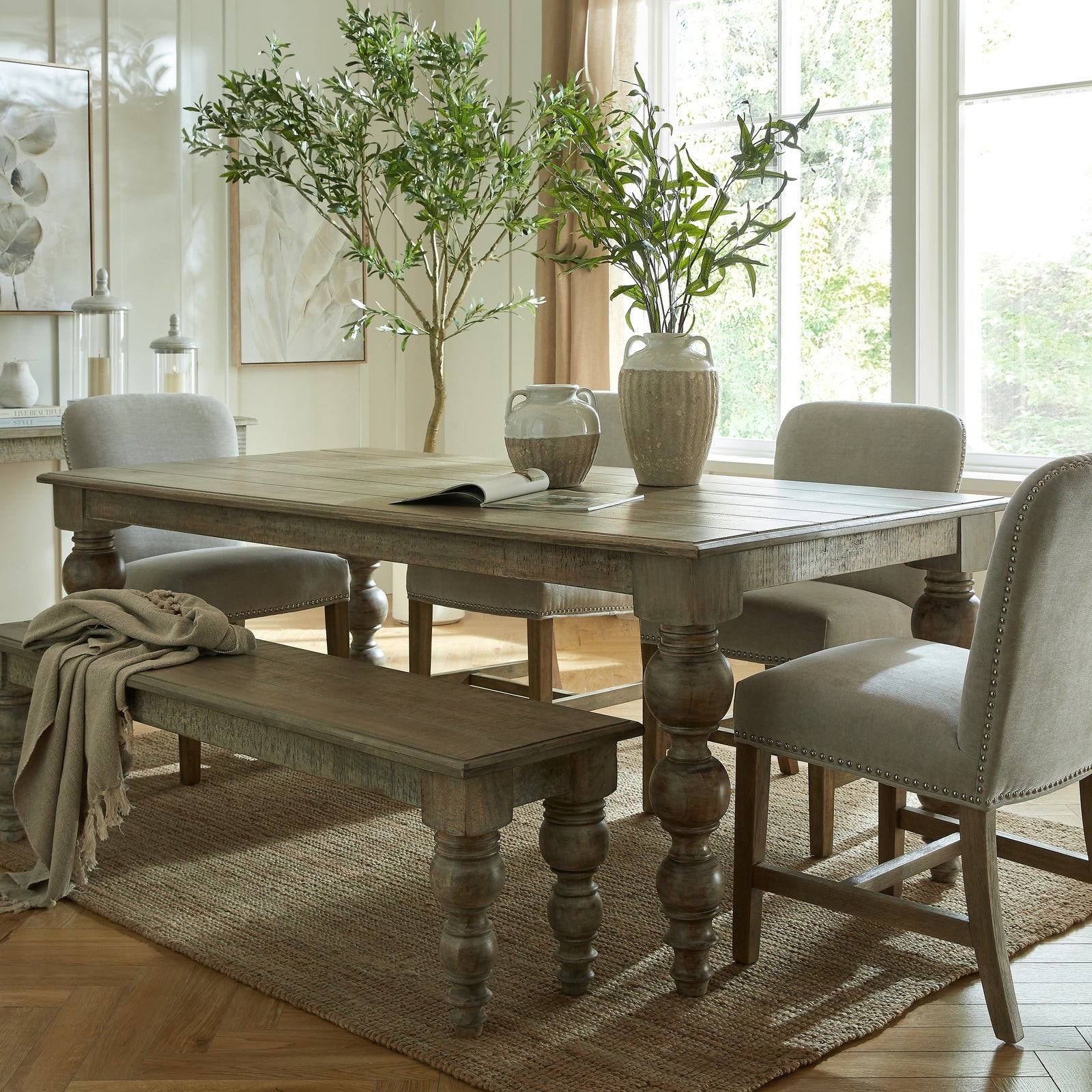Dining room with wooden table, chairs, and a bench in a bright room.