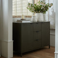 Dark gray sideboard with a vase of flowers and books on top, in a room with light-colored walls and wooden floor.