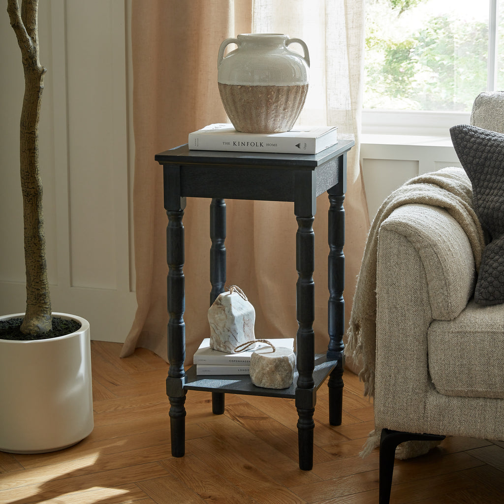 Small black side table with decorative items in a living room setting.