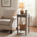 Beige armchair next to a wooden side table with a lamp and books in a living room setting.