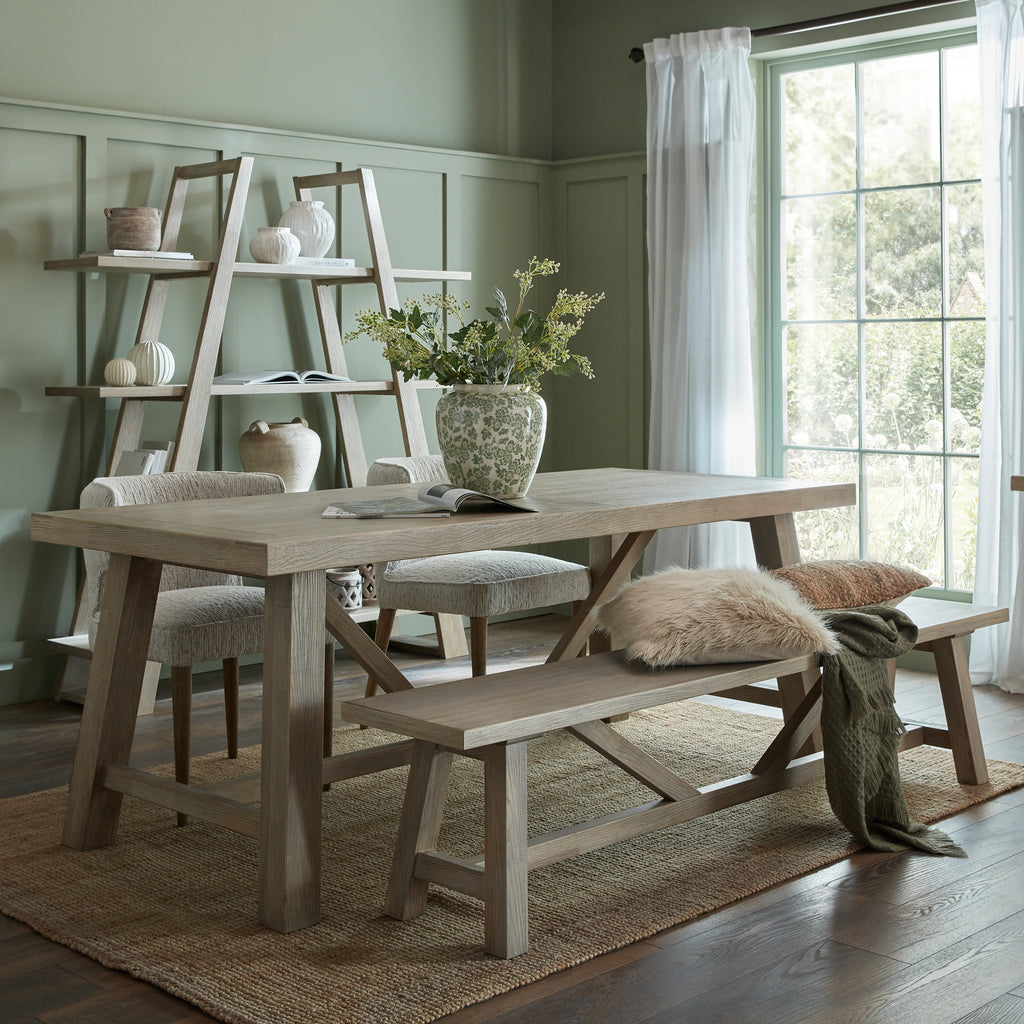 Dining room with wooden table, chairs, and bench in a well-lit room.