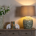 Decorative table with floral-patterned lamp and vase, books, and spherical objects on a wooden surface.