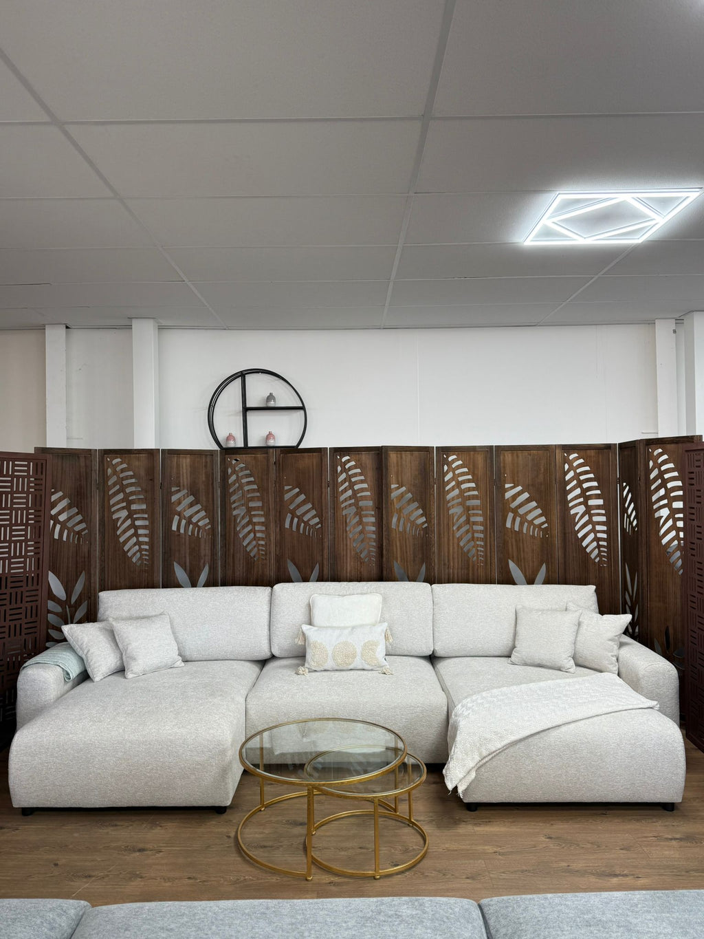 Modern living room with a white sectional sofa, glass coffee table, and decorative wall art.