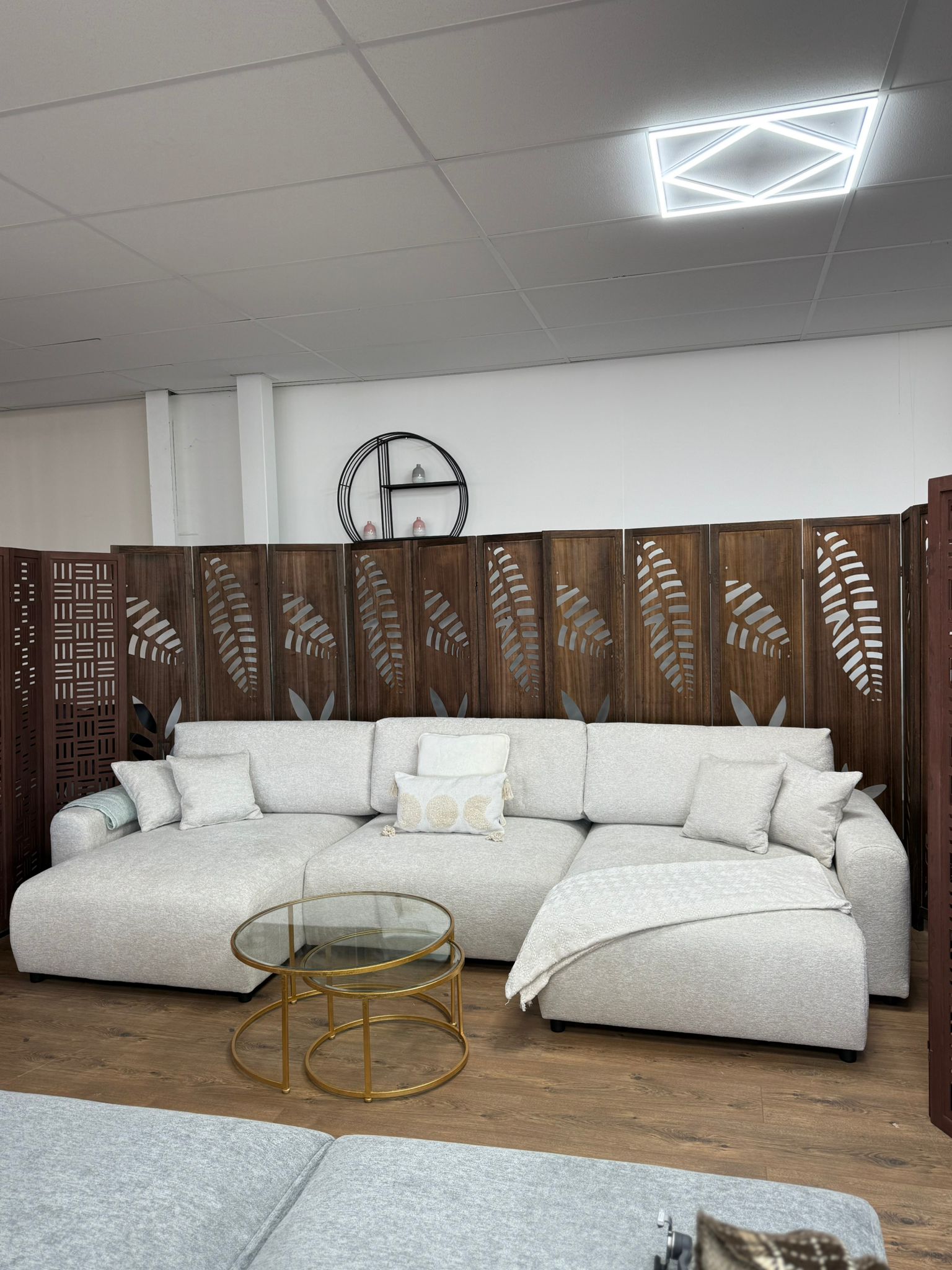 Modern living room with a white sectional sofa, glass coffee table, and decorative wall panels.