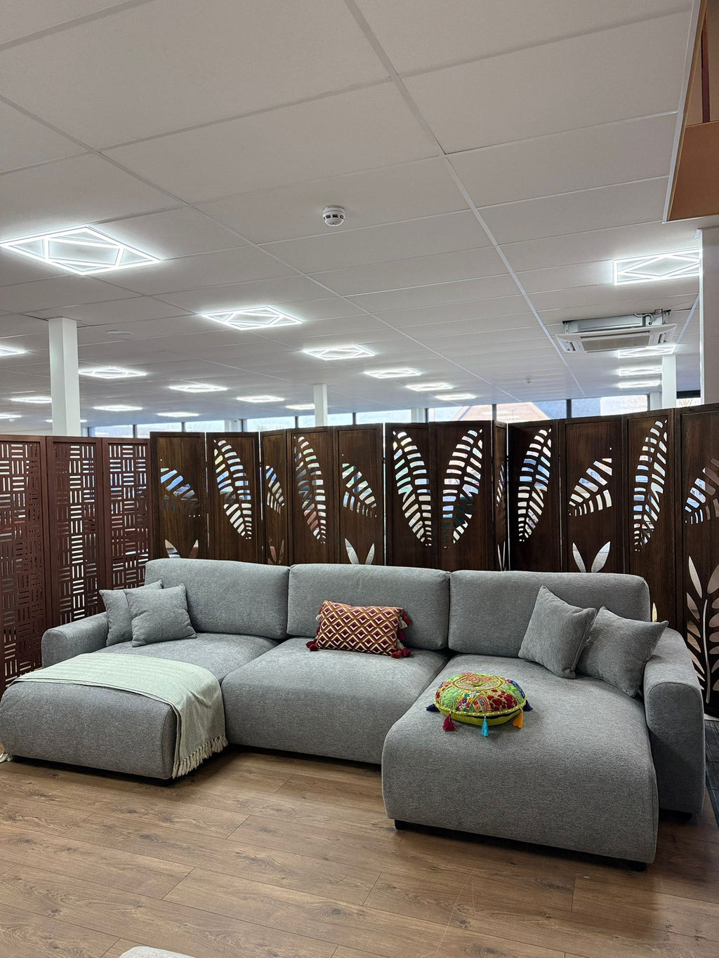 Gray sectional sofa in a modern office setting with decorative screens.