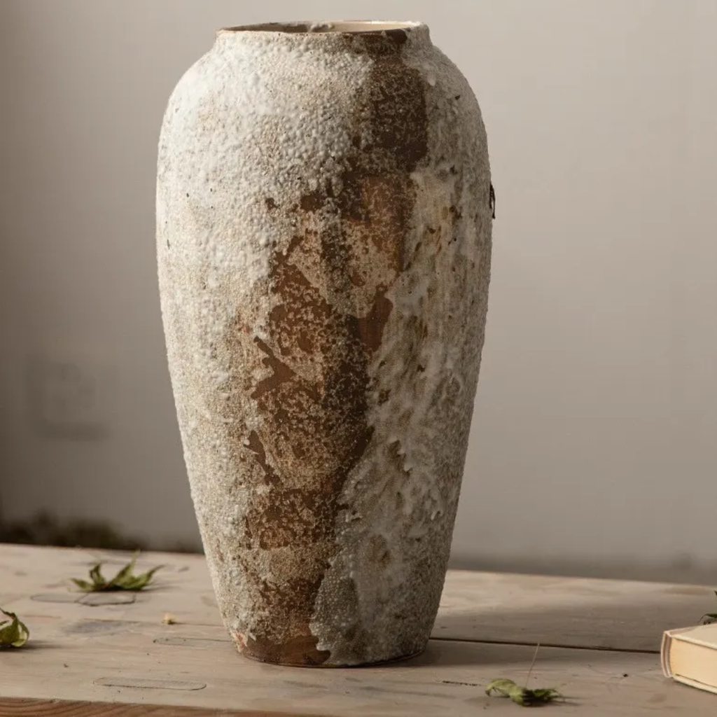 Textured ceramic vase on a wooden surface with a neutral background